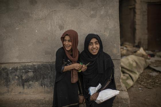 2 young girls in Iraq, one of the girls is blind and they are both smiling