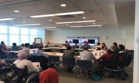SGPWD official delegation meeting. International Sign interpretation and captioning displayed on the screen. Participants sitting around a large square table.