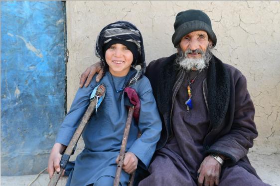 A young boy with crutches sitting with a blind old man