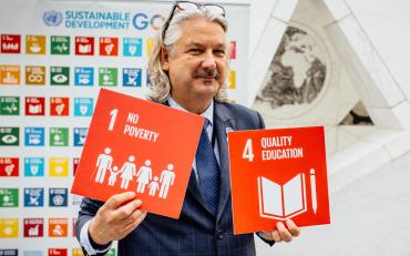 Colin Allen with SDG signs for Goal 1 No Poverty and Goal 4 Quality Education