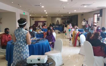 Amba Salelkar facilitating Bridge CRPD SDGs Bangladesh in a room full of participants sitting at round tables