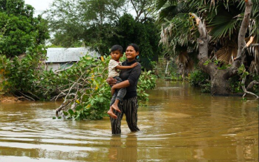 Women carrying child in flooded area
