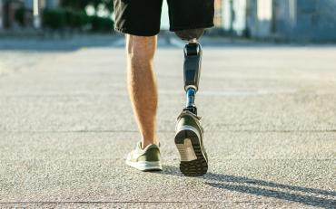 In the picture we can see the legs of a person using a prosthetics leg and running sneakers