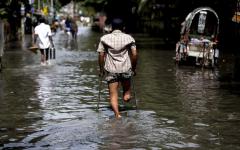 A person with disability using assistive technology in the middle of the flooded street. 